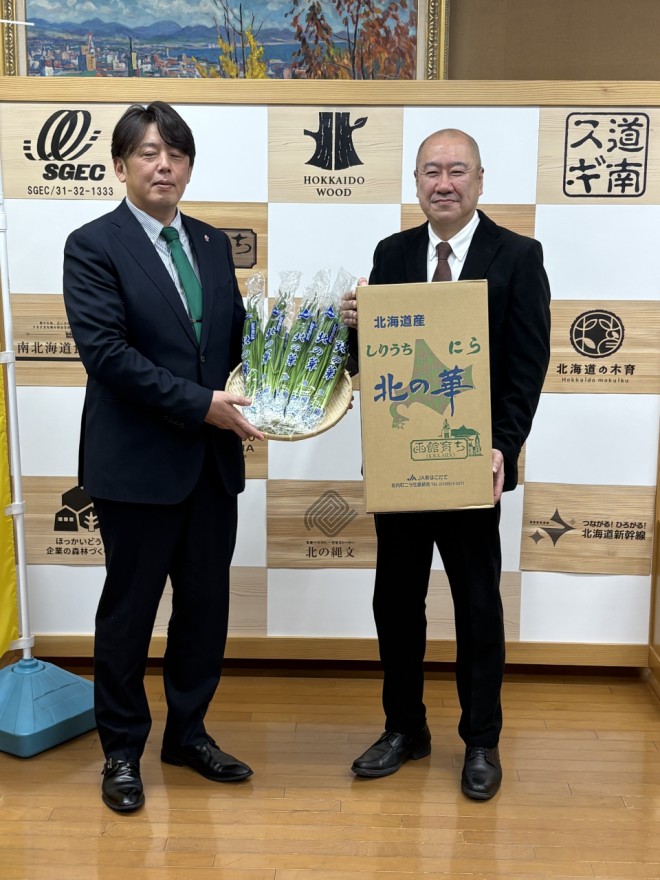 佐藤局長へ「しりうちにら北の華」を手渡す玉森組合長（左）