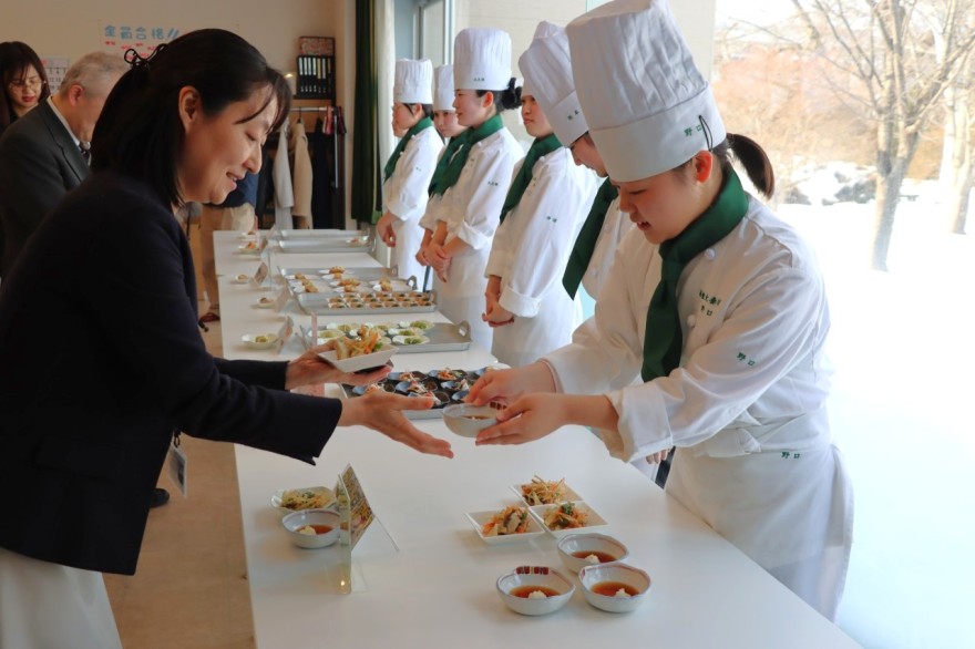 審査員や関係者に料理を手渡す生徒（右）