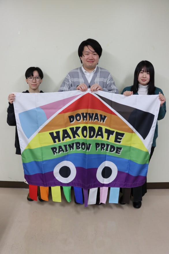 イカをモチーフにした虹色のフラッグを手にする笠島代表（中央）らＤＲＰメンバー