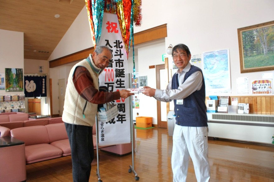 入館者にタオルを進呈する山田さん（右）